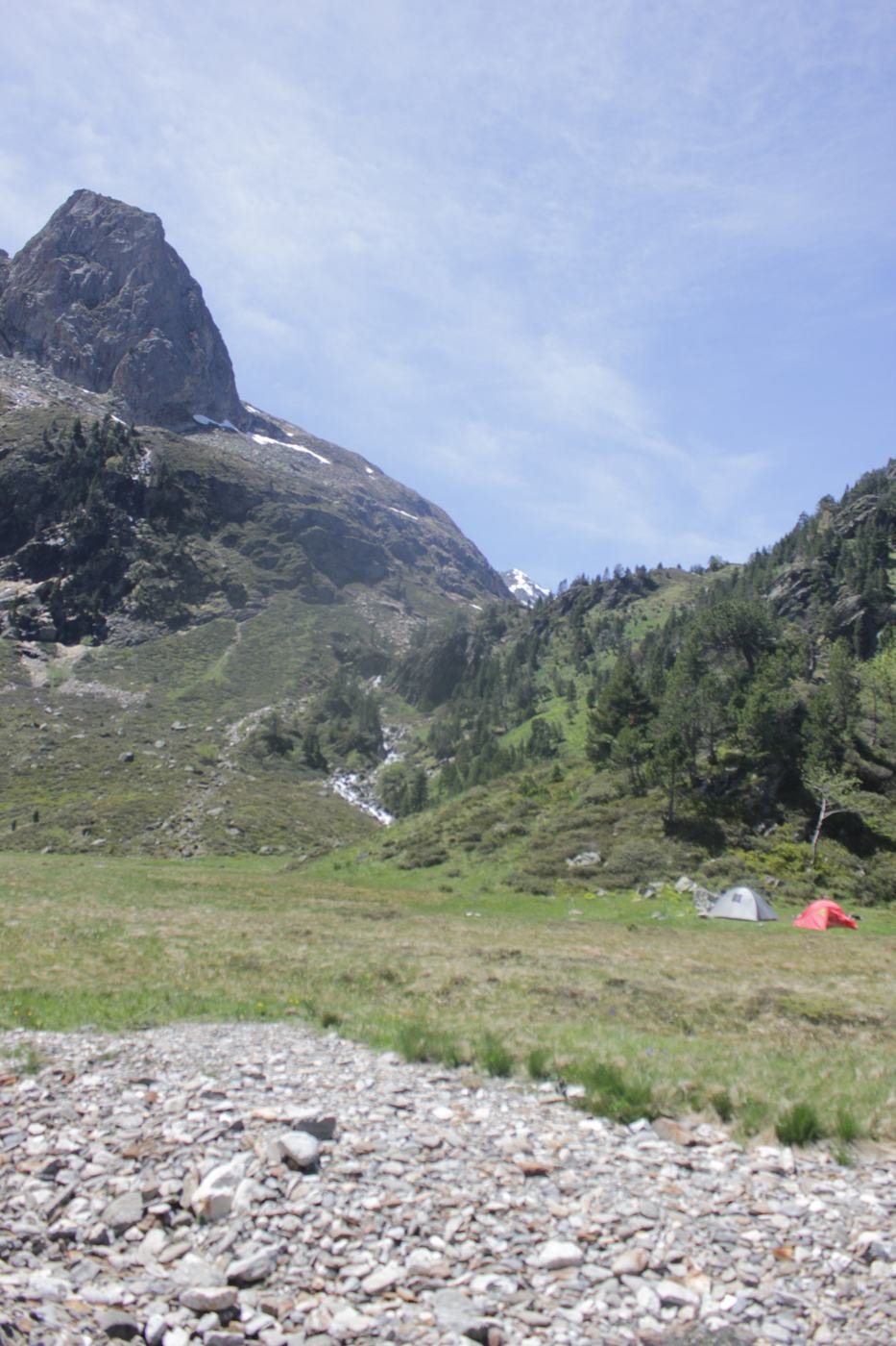Tentes plantées dans un vallon au pied d'un pic rocheux