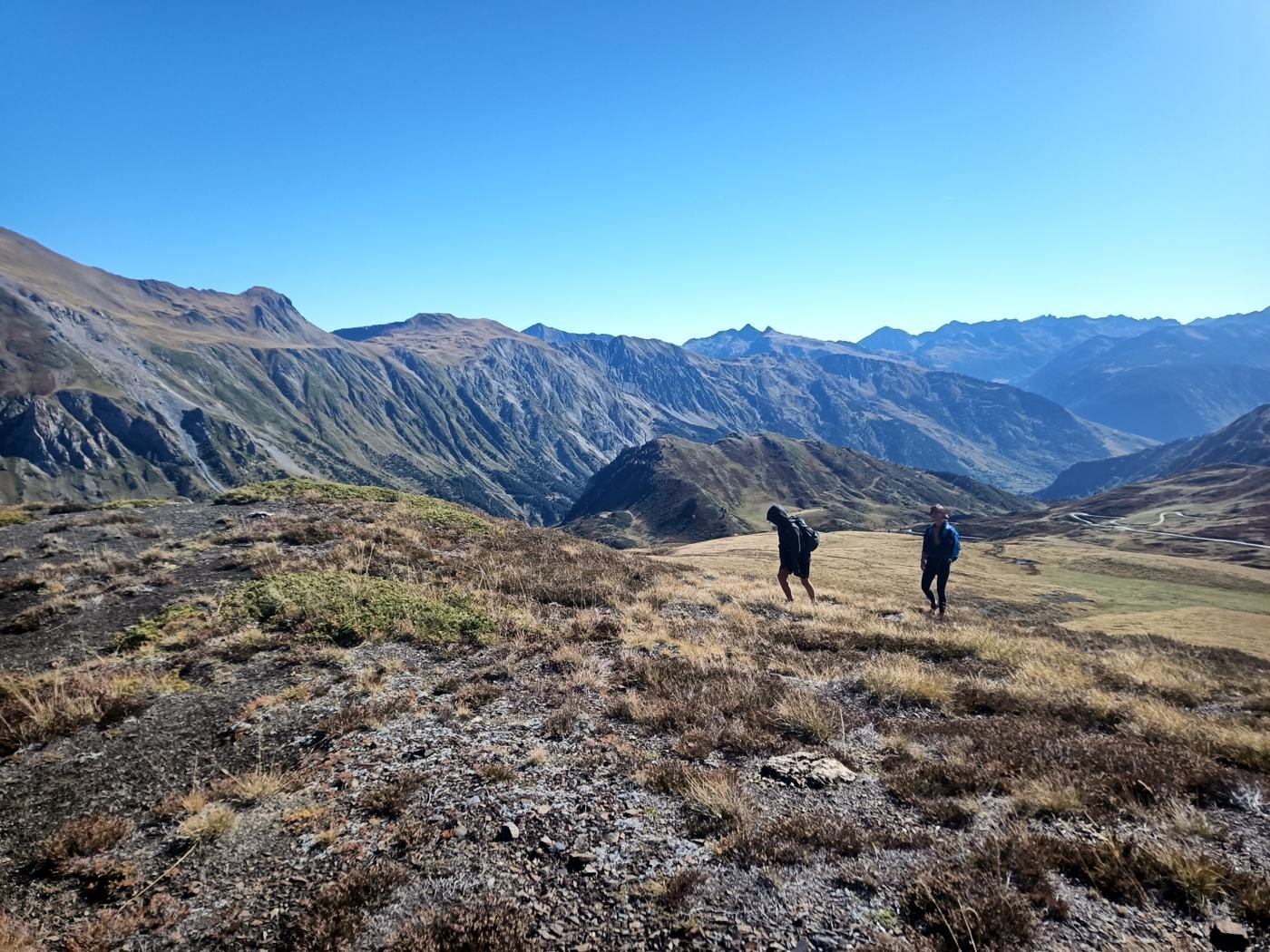 Deux randonneurs avec leur sac sur un plateau d'altitude face aux montagnes