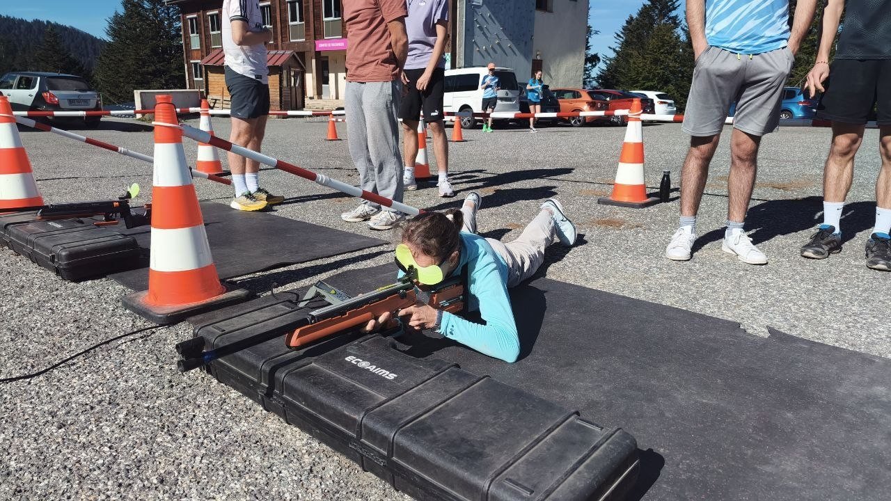 Une participante allongée au pas de tir du biathlon, carabine laser en main