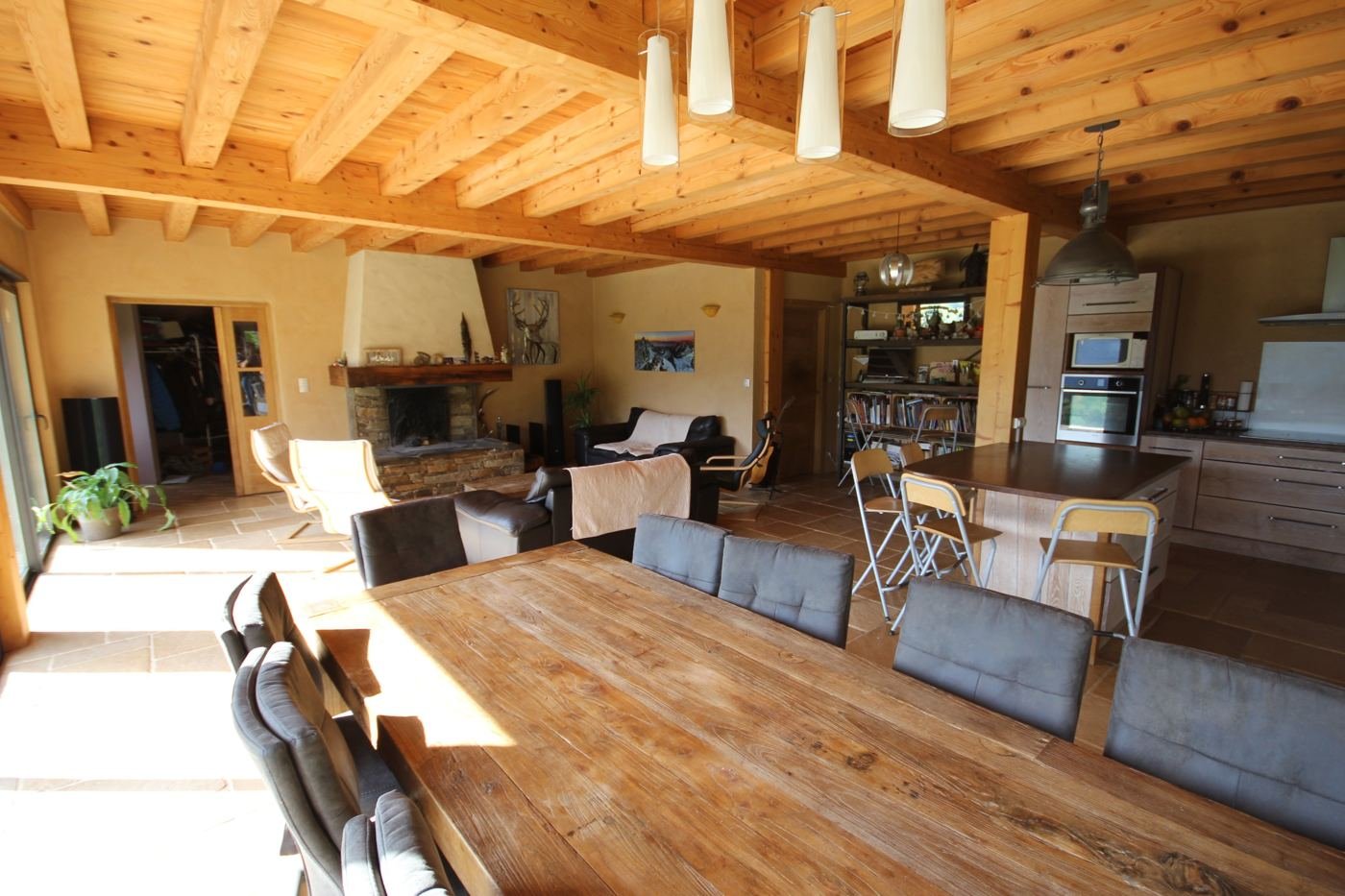 La grande pièce à vivre du gîte, table en bois et baies vitrées