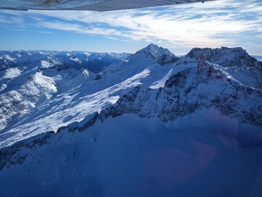 Sous l'aile, une grande crête enneigée dans la lumière rasante