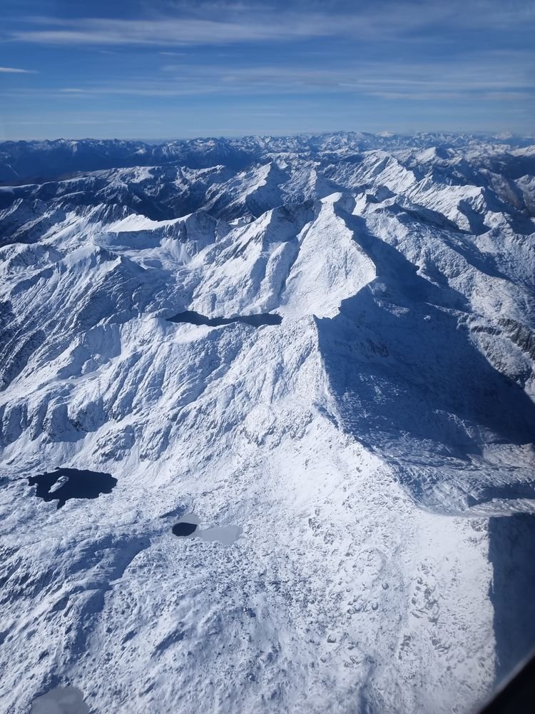 Une longue arête, et trois lacs posés dans la neige à ses pieds
