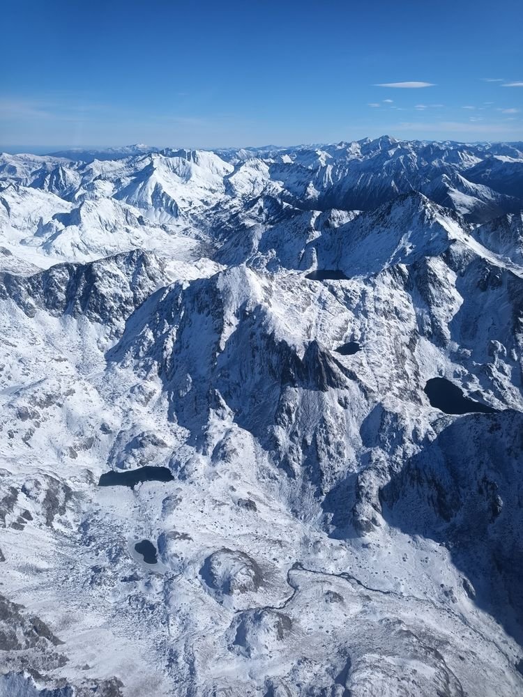 Lacs sombres et torrent qui serpente dans la neige fraîche